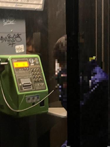 公衆電話から覗き込む顔