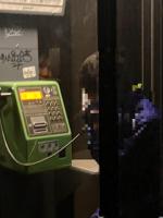 公衆電話から覗き込む顔の画像